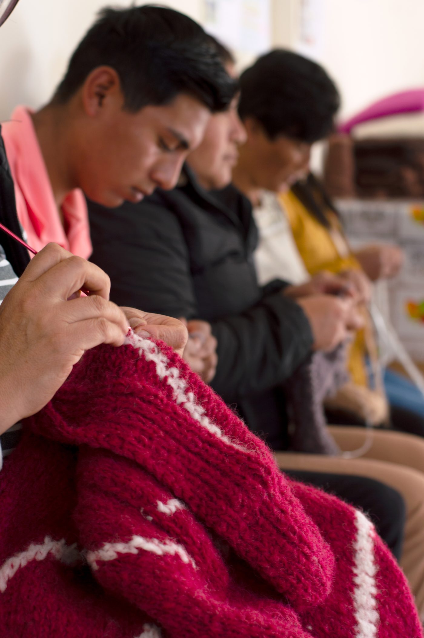 Hands knitting a wine-red garment